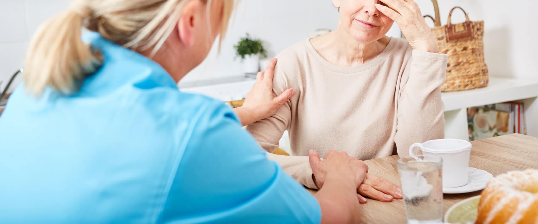 Carer holding older person at breakfast table