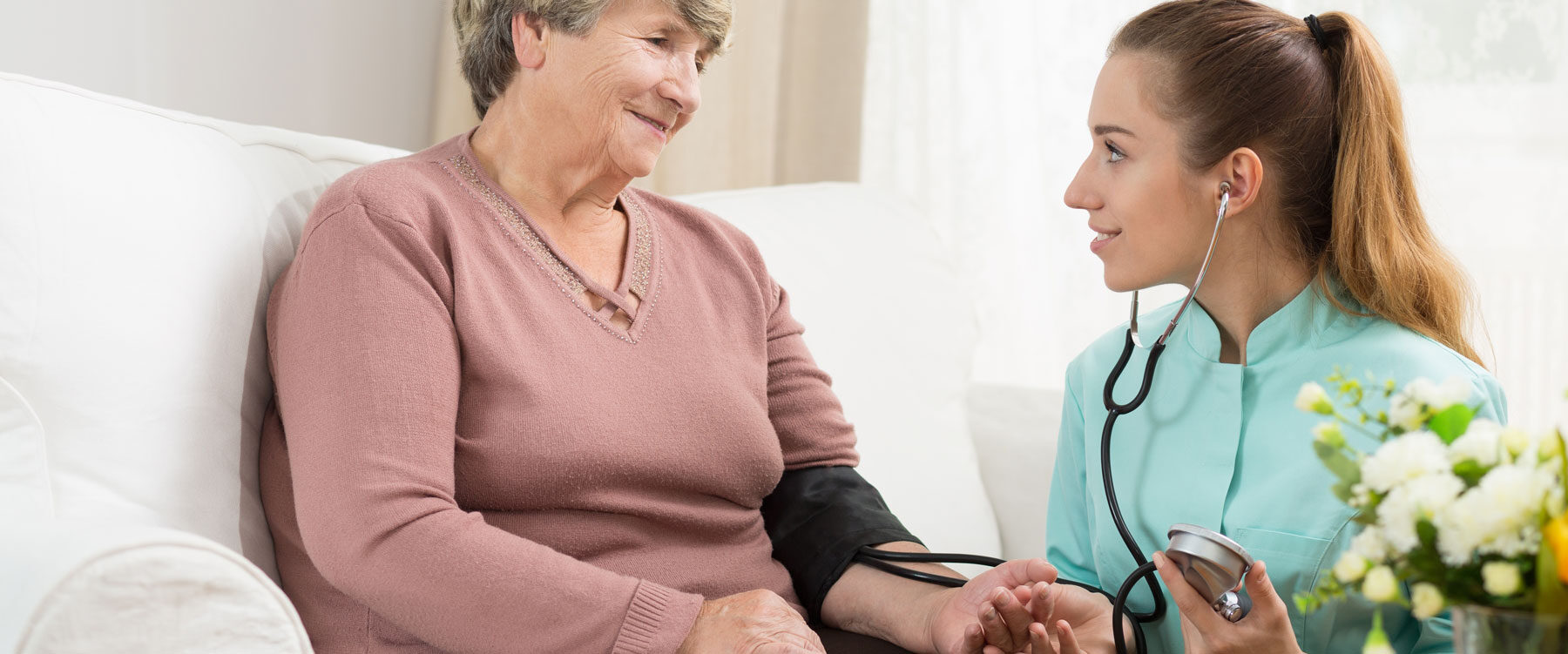 Carer checking older person's blood pressure
