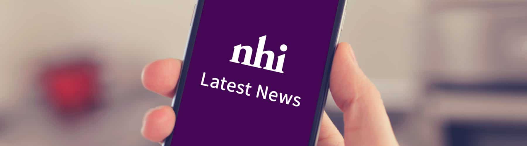 Hand holding mobile phone with Nursing Homes Ireland news on it
